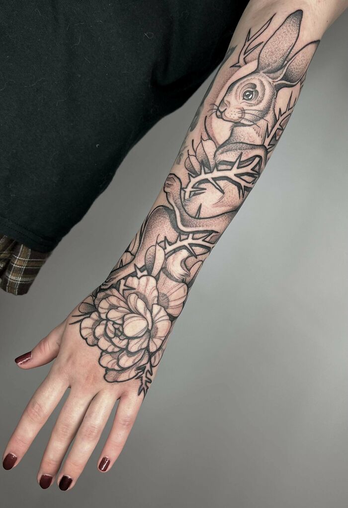 Black and gray trippy tattoo of a rabbit and flower on a forearm.