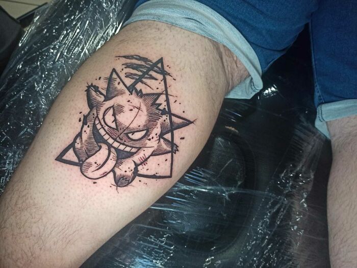 Psychedelic art tattoo featuring a cartoonish creature, designed with geometric elements on a person's thigh.