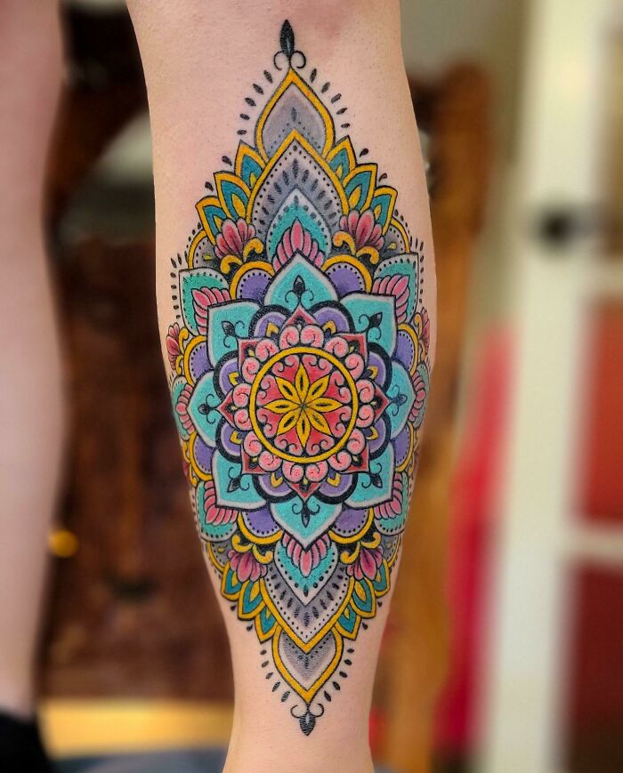 Colorful trippy tattoo of a mandala design on a leg, showcasing intricate patterns and vibrant colors.
