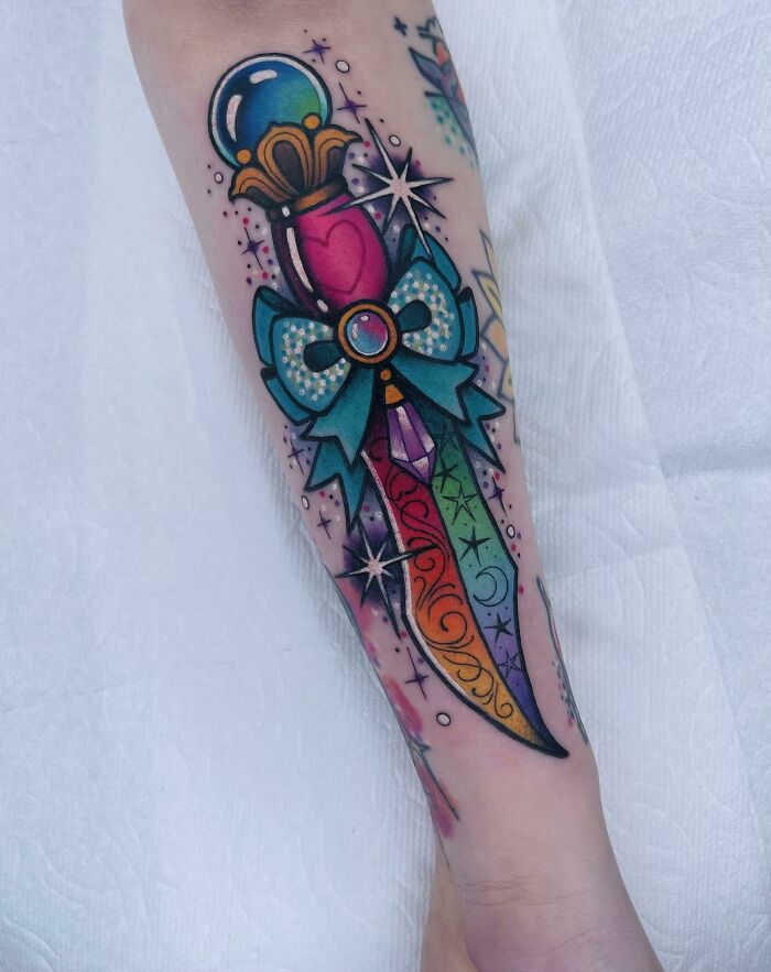 Colorful rainbow dagger arm tattoo with stars, featuring trippy tattoo design elements.