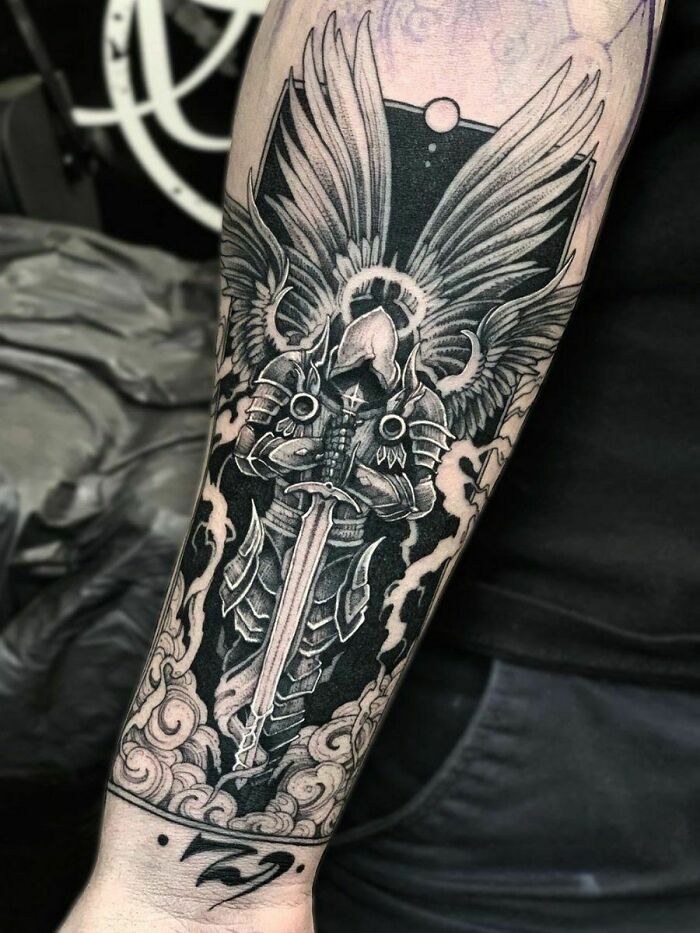 Trippy tattoo of Tyrael from Diablo on forearm, showcasing detailed wings and armor.