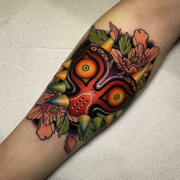 Colorful trippy tattoo featuring a vibrant psychedelic mask with floral elements.