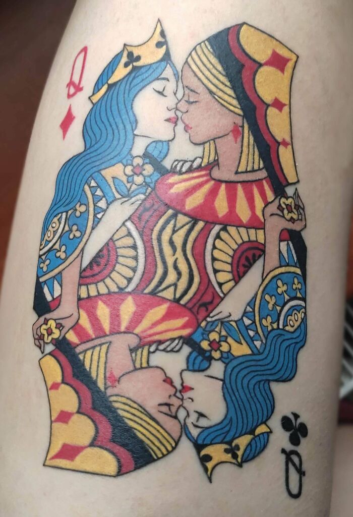 Trippy tattoo of two kissing queens from a deck of cards in vibrant colors on skin.