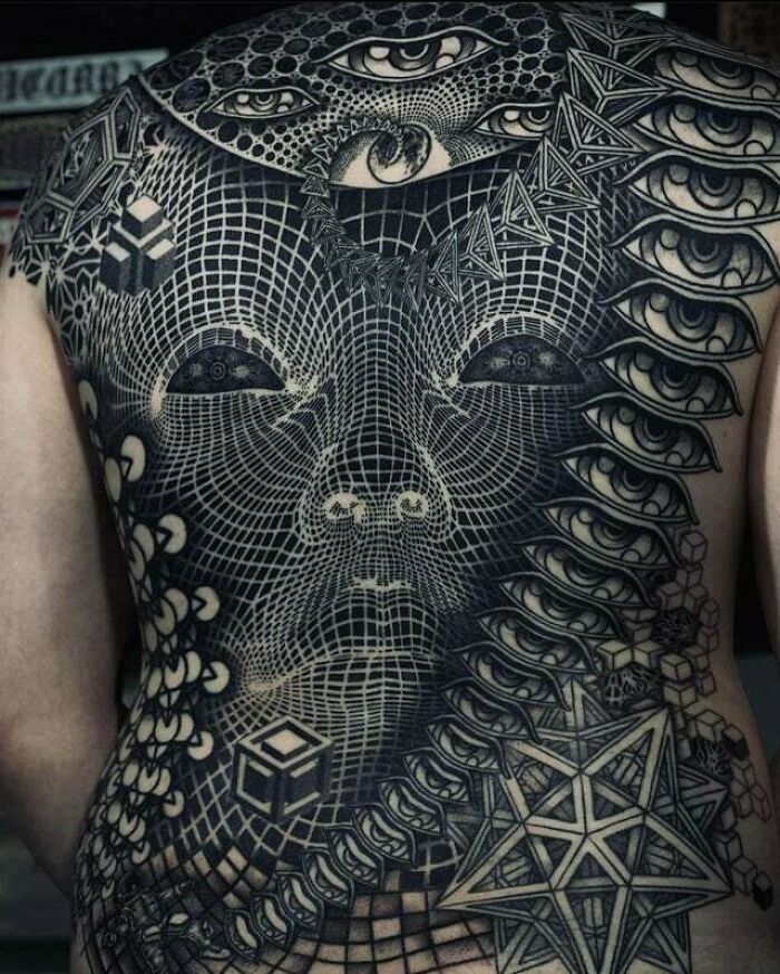 Psychedelic art tattoo featuring geometric patterns and multiple eyes covering a person's back.