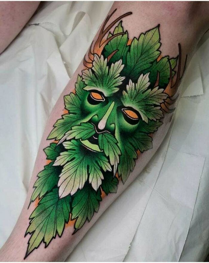 Green man tattoo design with vibrant leaves, showcasing psychedelic art on forearm.