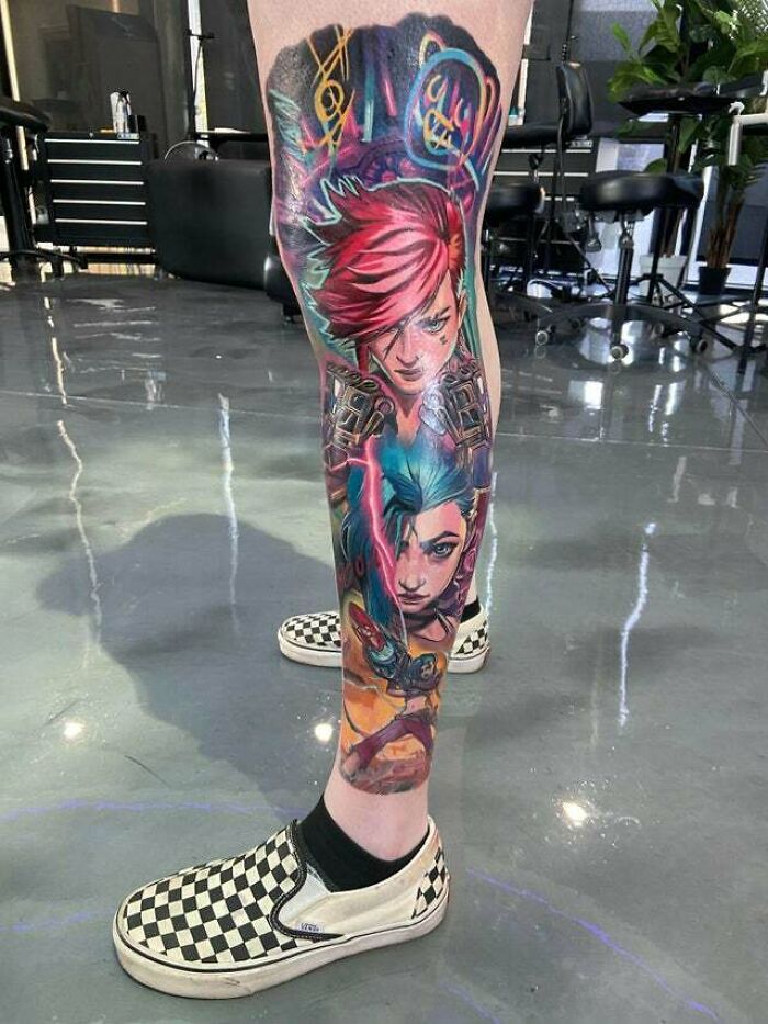 Trippy tattoo sleeve featuring vibrant anime-style characters and graffiti elements on a person's leg in a tattoo studio.