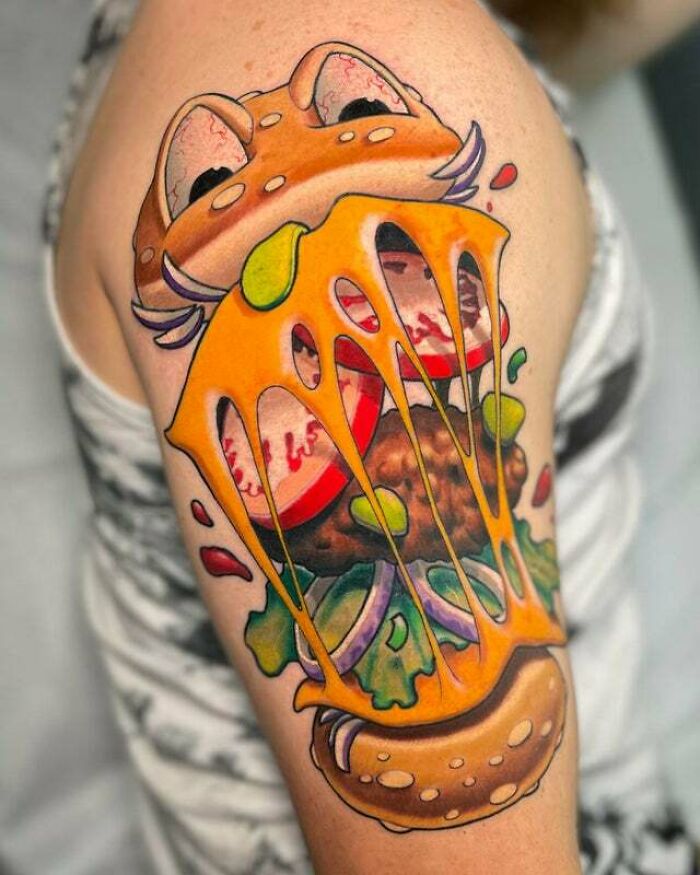 Colorful trippy tattoo of a cheeseburger on an arm, featuring vibrant cheese and burger details.