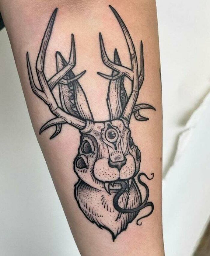 Trippy tattoo of an evil monster deer on an arm, showcasing intricate antlers and detailed design.