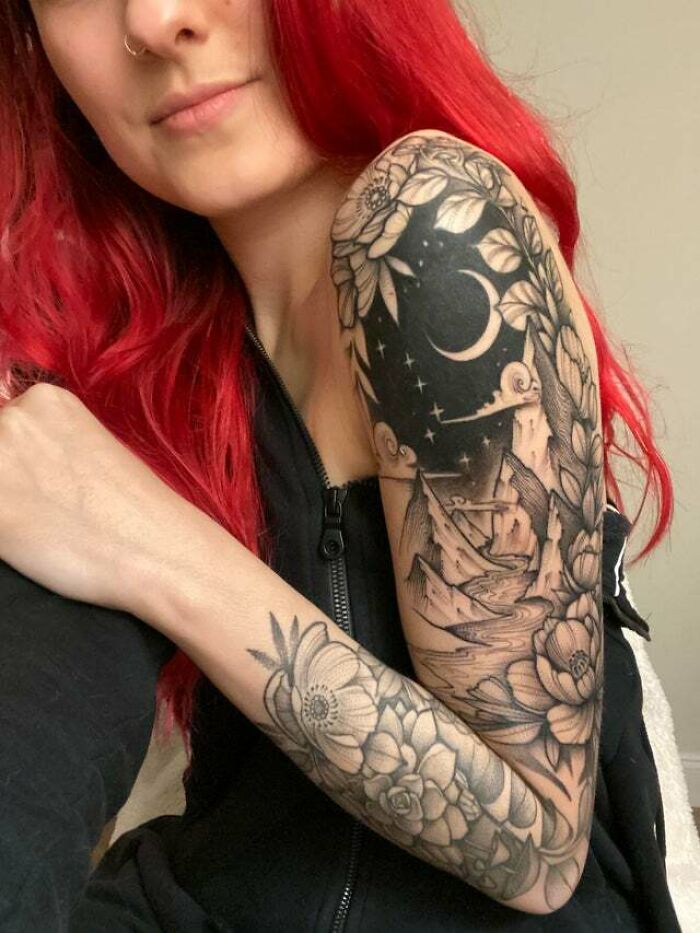 Person with vibrant arm sleeve tattoo featuring trippy flowers, nature, and night theme.