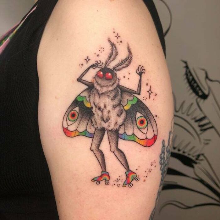 A psychedelic moth tattoo with colorful wings and roller skates on an arm.