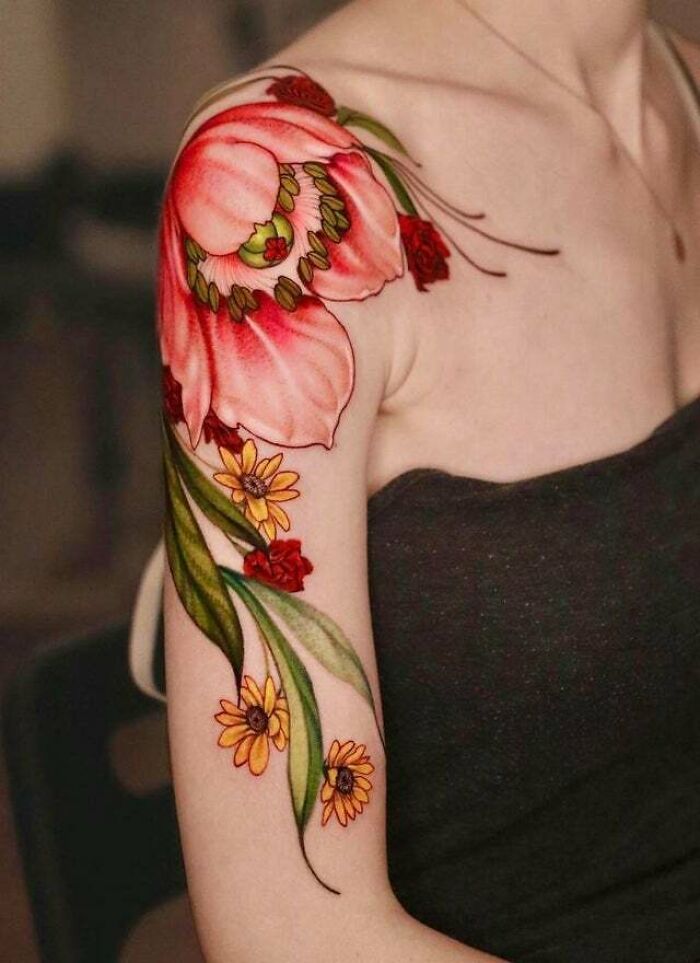 Trippy tattoo design featuring colorful red and yellow flowers on an arm and shoulder.