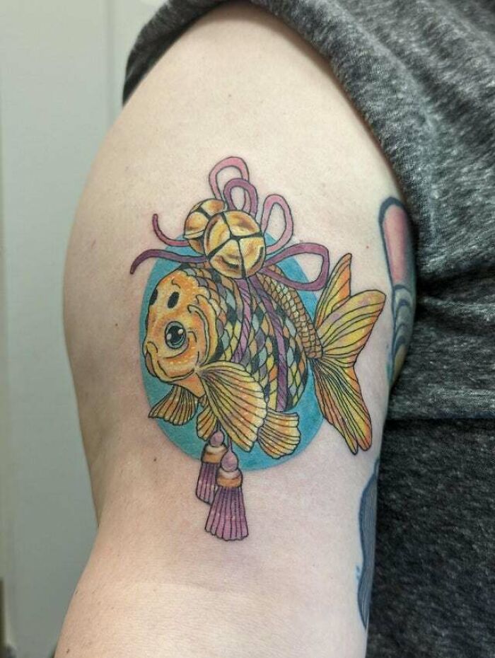 Colorful psychedelic goldfish tattoo on arm, featuring intricate patterns and vibrant hues.