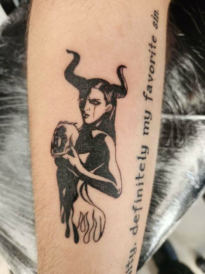 Psychedelic tattoo of a horned figure holding a skull, with text beside it.