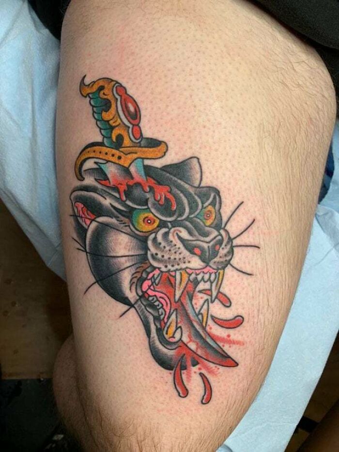 Trippy tattoo of a panther with a dagger through its head, featuring vivid colors and intricate design on the arm.