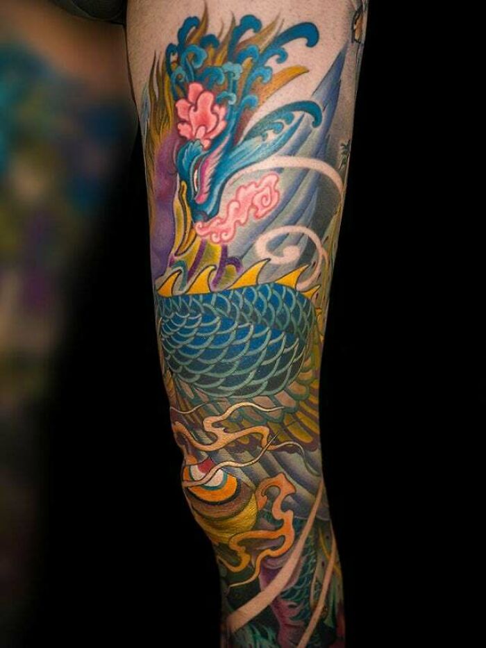 Vibrant psychedelic tattoo featuring an intricate design of a phoenix with vivid colors on an arm sleeve.