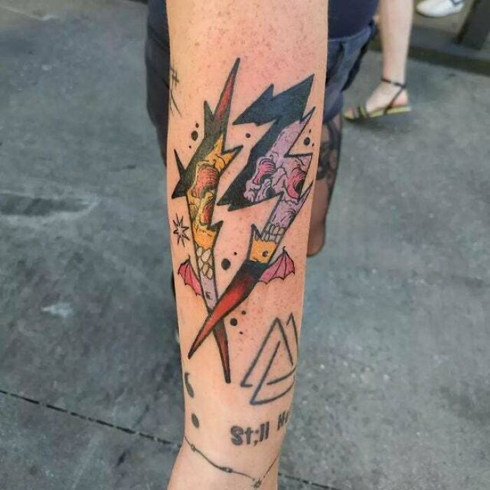 Unique trippy tattoo with vivid colors and abstract design on a forearm, featuring lightning bolt shapes and intricate details.