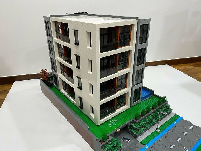 Detailed LEGO building of a modern multi-story building with greenery and a parking area, showcasing incredible LEGO builds.