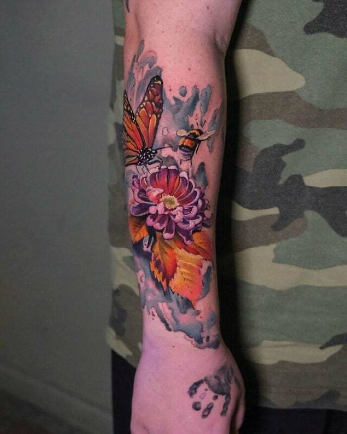 Trippy tattoo of flowers with a bee and butterfly on arm, featuring vibrant colors and intricate details.