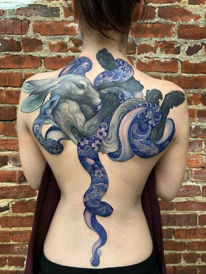 Back tattoo featuring a trippy, psychedelic art design with a rabbit and swirling patterns.