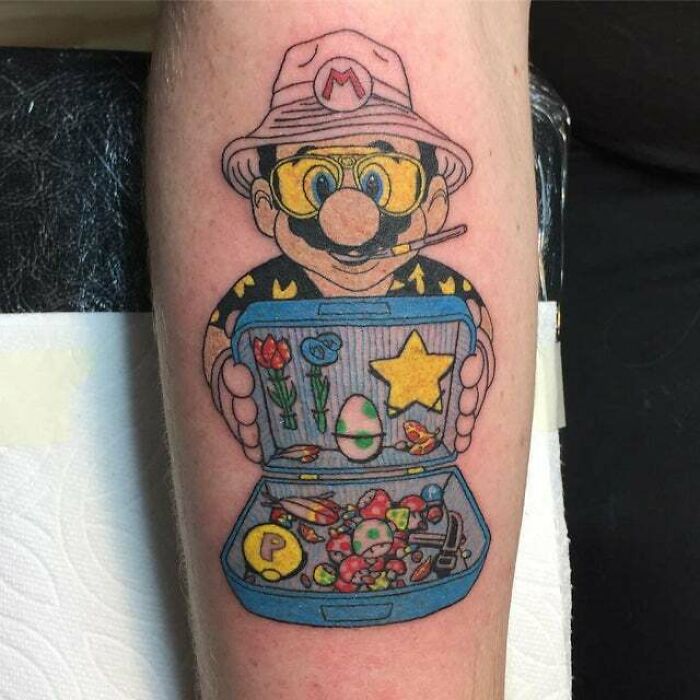 Trippy tattoo of a cartoon character in a hat holding a suitcase with colorful items on a person's arm.