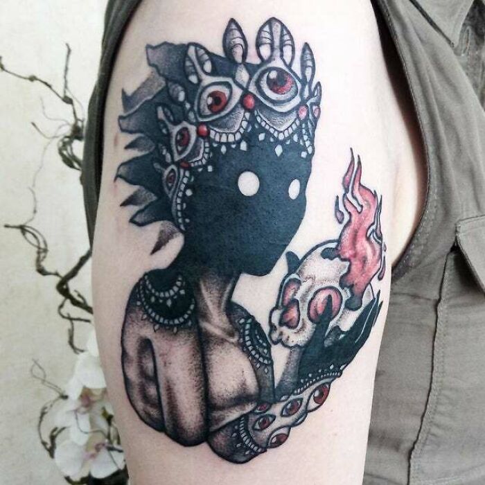 Psychedelic art tattoo of a mysterious figure holding a flaming skull, featuring intricate patterns and vibrant details.