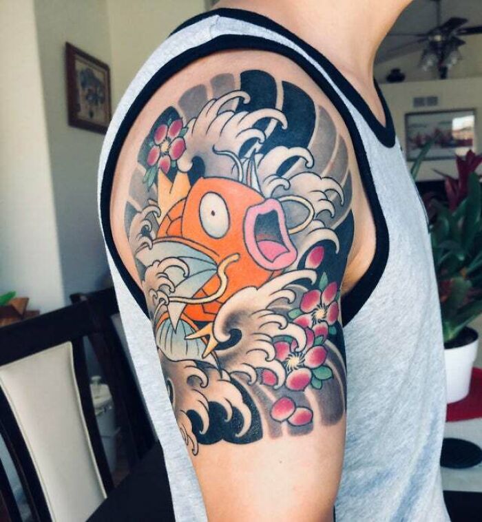 Colorful tattoo of an orange fish with waves and flowers on arm, showcasing psychedelic art style.