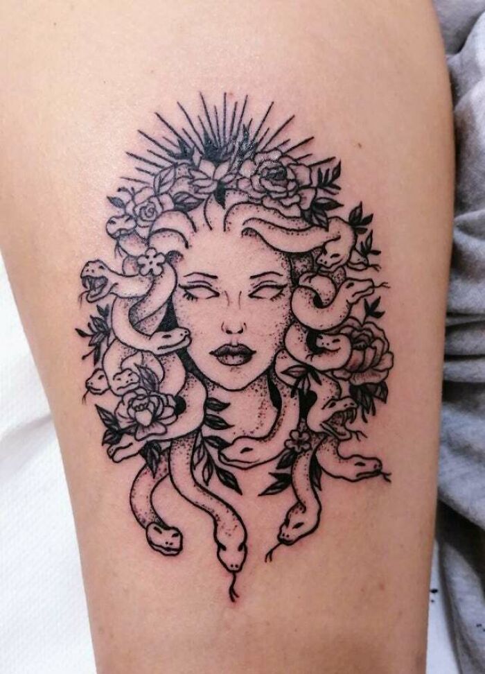 Tattoo of a Medusa head with snake hair and floral accents, showcasing psychedelic art style.