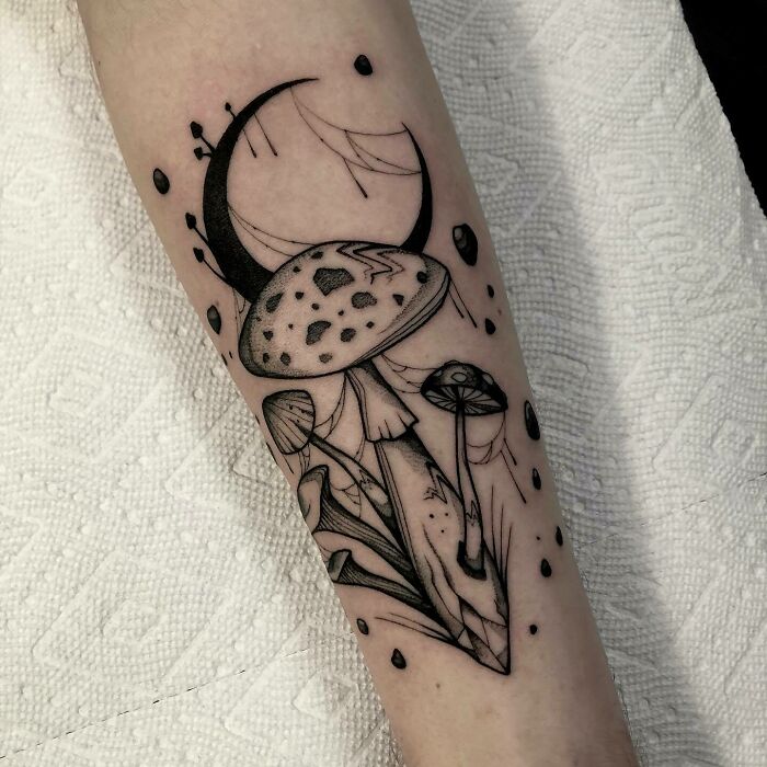 Trippy tattoo featuring mushrooms and a crescent moon on an arm.