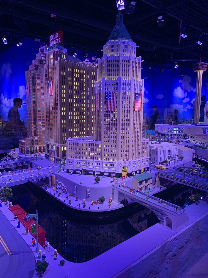 Detailed LEGO buildings with bridges and miniature figures displayed under blue lighting, showcasing incredible LEGO builds as art.