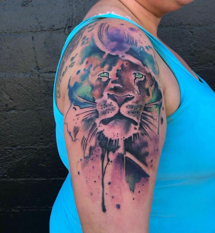 Colorful trippy lion tattoo on shoulder, featuring vibrant hues and an abstract design.