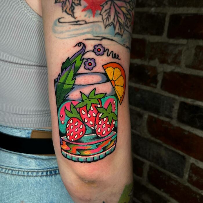Colorful trippy tattoo of strawberries and citrus in a jar on an arm, blending vibrant and surreal elements.
