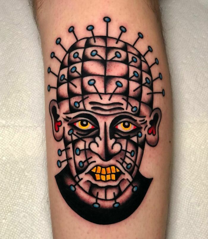 Trippy tattoo of a man's face with needle-like designs on a leg.