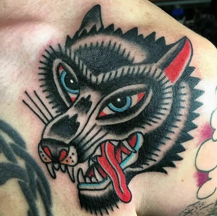 Colorful trippy wolf chest tattoo with bold black and red accents, showcasing intricate design and vibrant details.