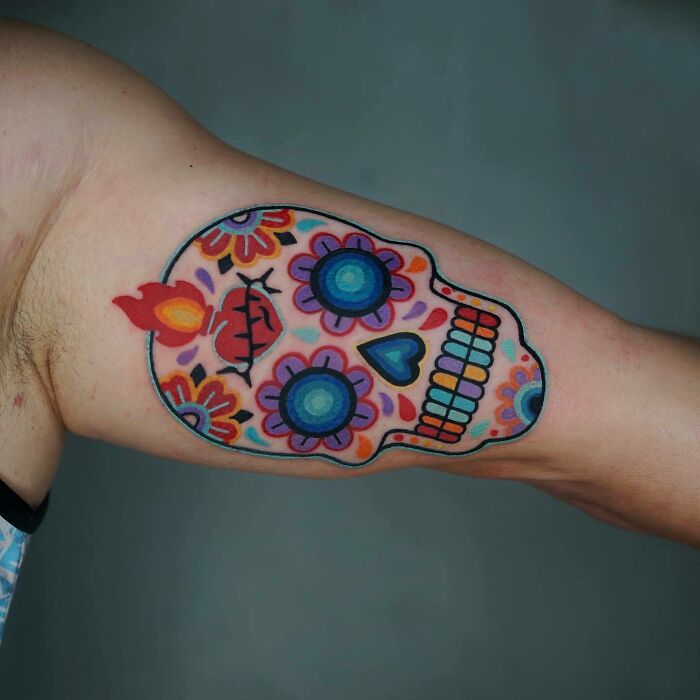Colorful trippy tattoo of a sugar skull on arm, featuring vibrant designs and patterns.