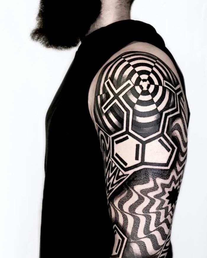 Trippy tattoo with geometric and optical illusion patterns on a person's arm and shoulder.