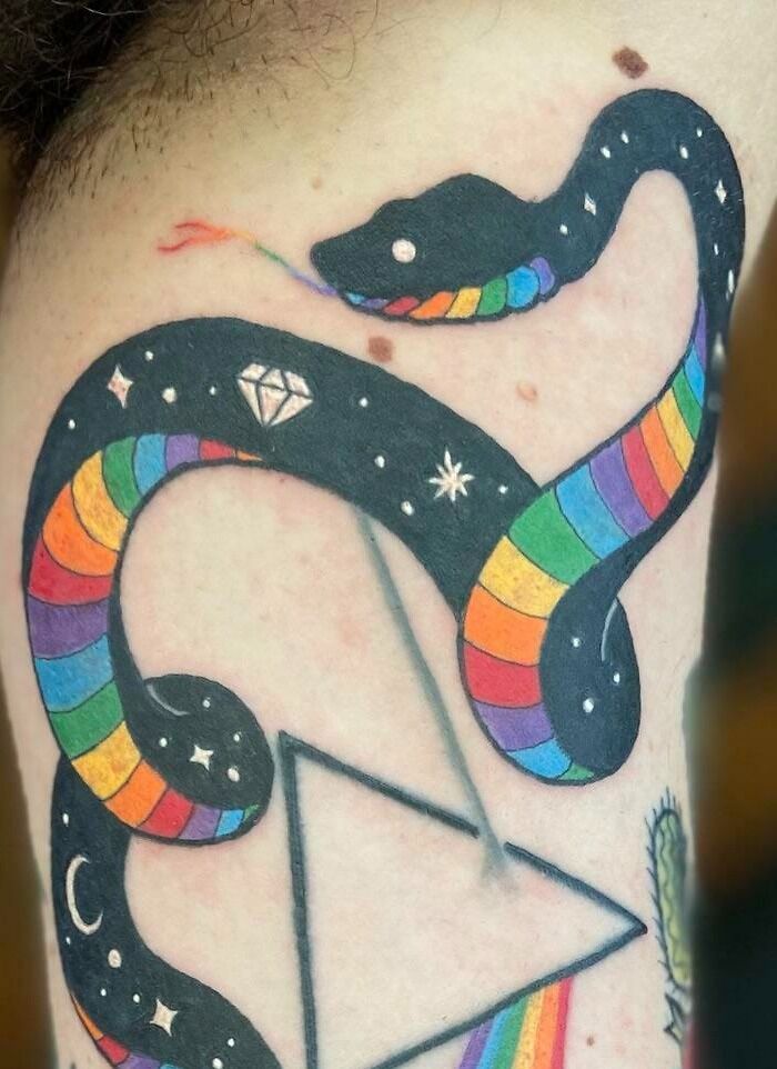Colorful trippy tattoo of a snake with rainbow and diamond design on a leg, featuring cosmic elements.
