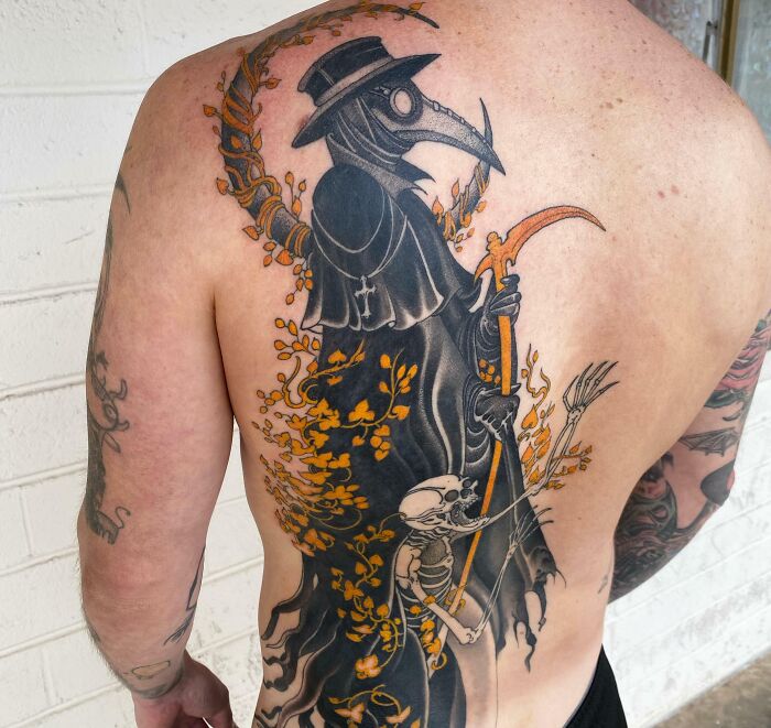 Back tattoo featuring psychedelic art of a plague doctor with orange accents and intricate designs.
