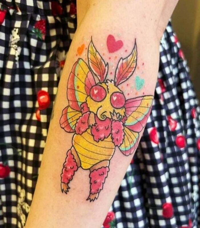 Trippy tattoo of rosy maple mothman with hearts on arm.