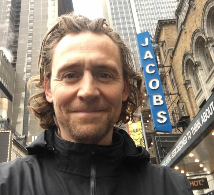 Male celebrity smiling in an urban setting, representing the smartest celebrities known for being talented and intelligent.