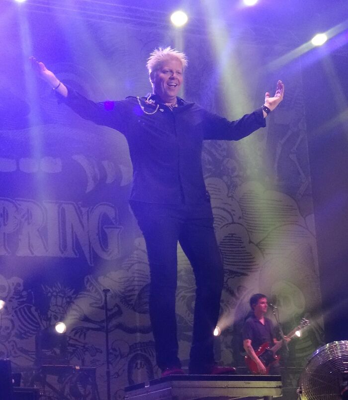 Performer on stage with arms outstretched, spotlight shining, representing smartest celebrities known for talent and intelligence.