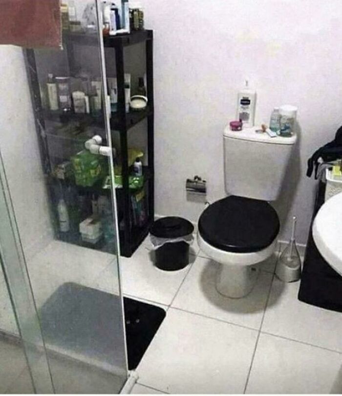 Bathroom scene with black and white toilet and matching black trash can blending into the floor for camouflaged effect.