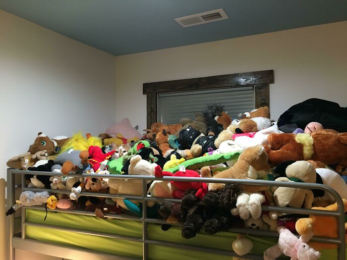 Bed covered with numerous perfectly camouflaged stuffed animals blending into each other, challenging what you see.