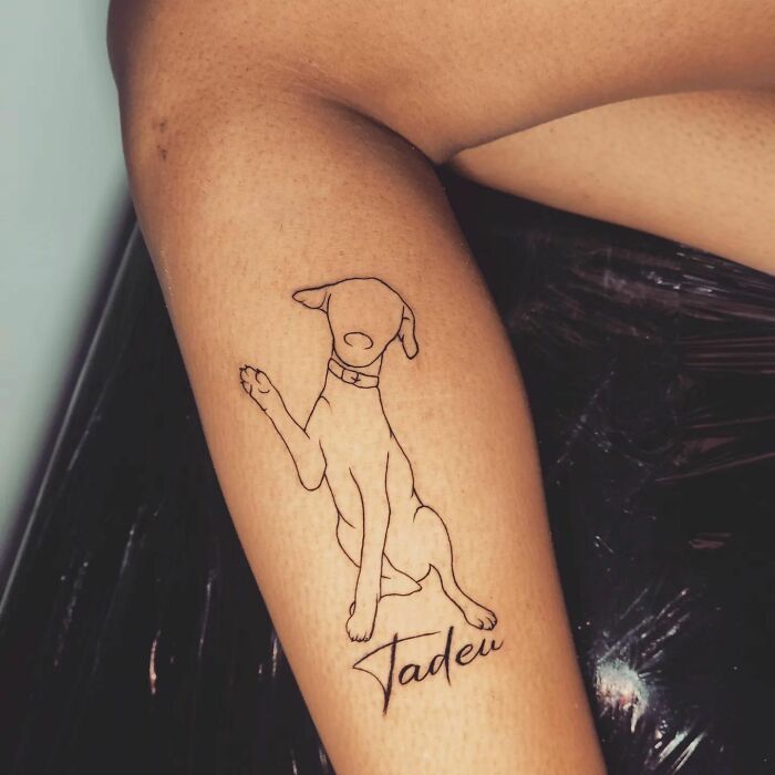 Minimalist pet tattoo of a dog on an arm, celebrating furry friends.