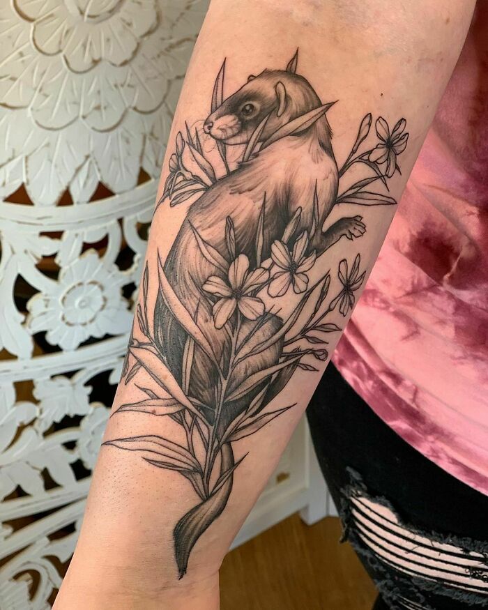 Pet tattoo featuring a ferret with detailed floral design on a person's forearm.