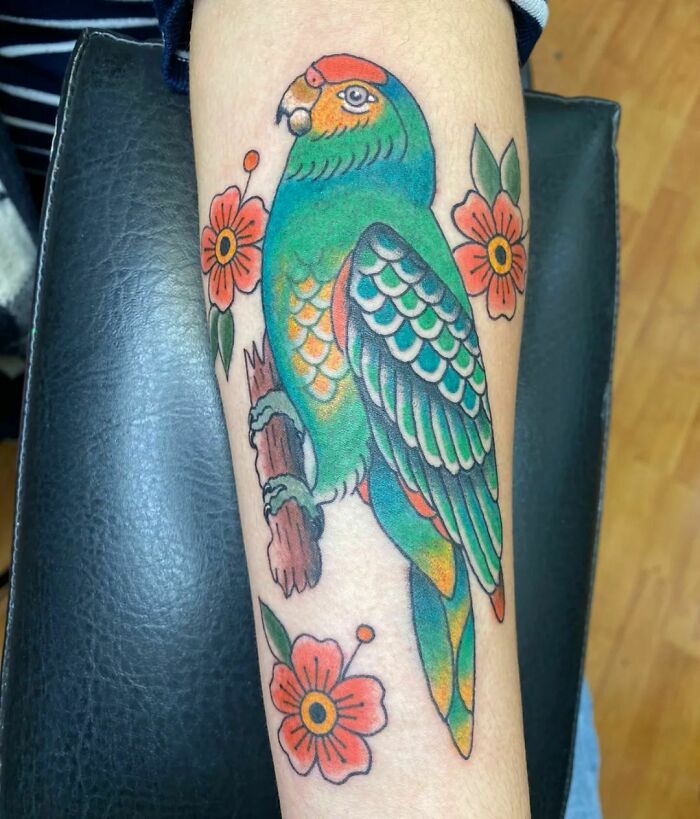 Colorful pet tattoo of a parrot with flowers, celebrating furry friends.