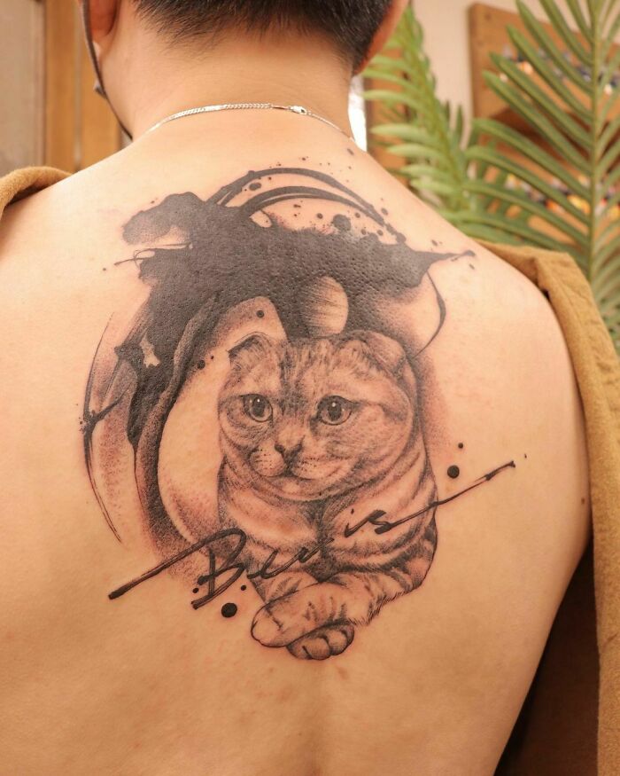 Cat tattoo on back, featuring detailed portrait with abstract elements, immortalizing a cherished pet.