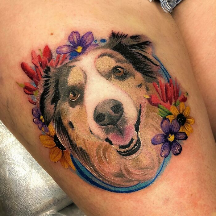 Pet tattoo of a dog's face surrounded by colorful flowers, celebrating furry friends.