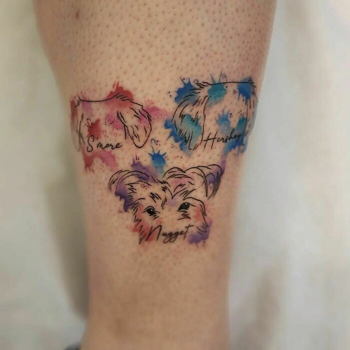 Tattoo featuring colorful sketches of three dogs' faces, highlighting the bond between humans and pets.
