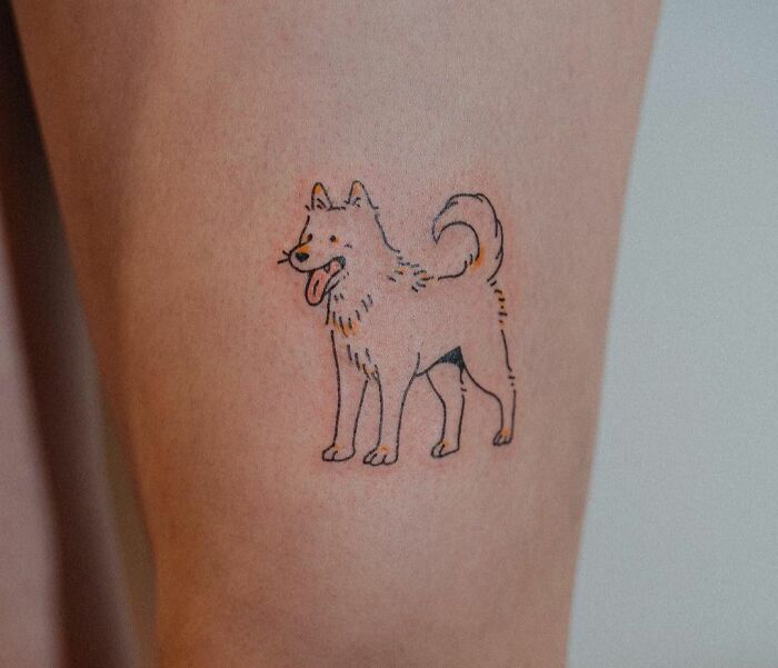Pet tattoo featuring a cheerful dog on a person's leg, celebrating furry friends.