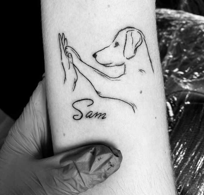 Line art pet tattoo of a dog named Sam on forearm, symbolizing furry friends.